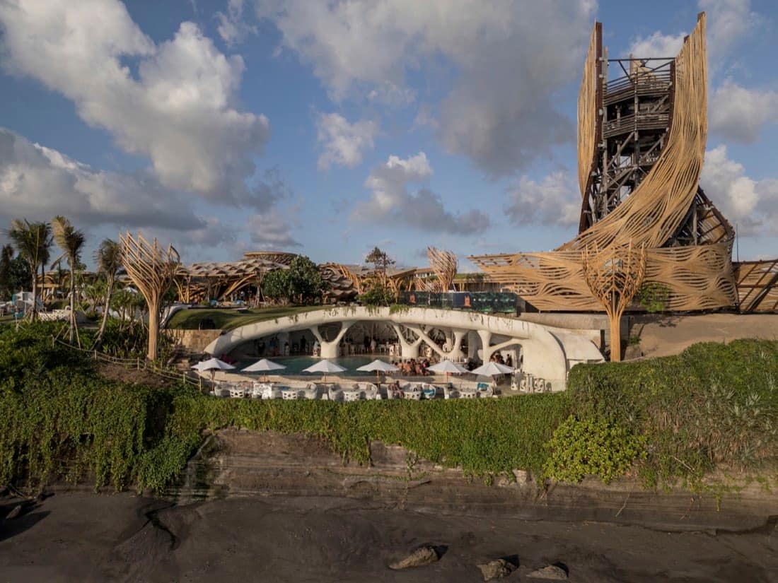 Side elevation of the Luna Beach Club vortex and pool deck on the cliff edge above dark rocks, with the bamboo tower behind