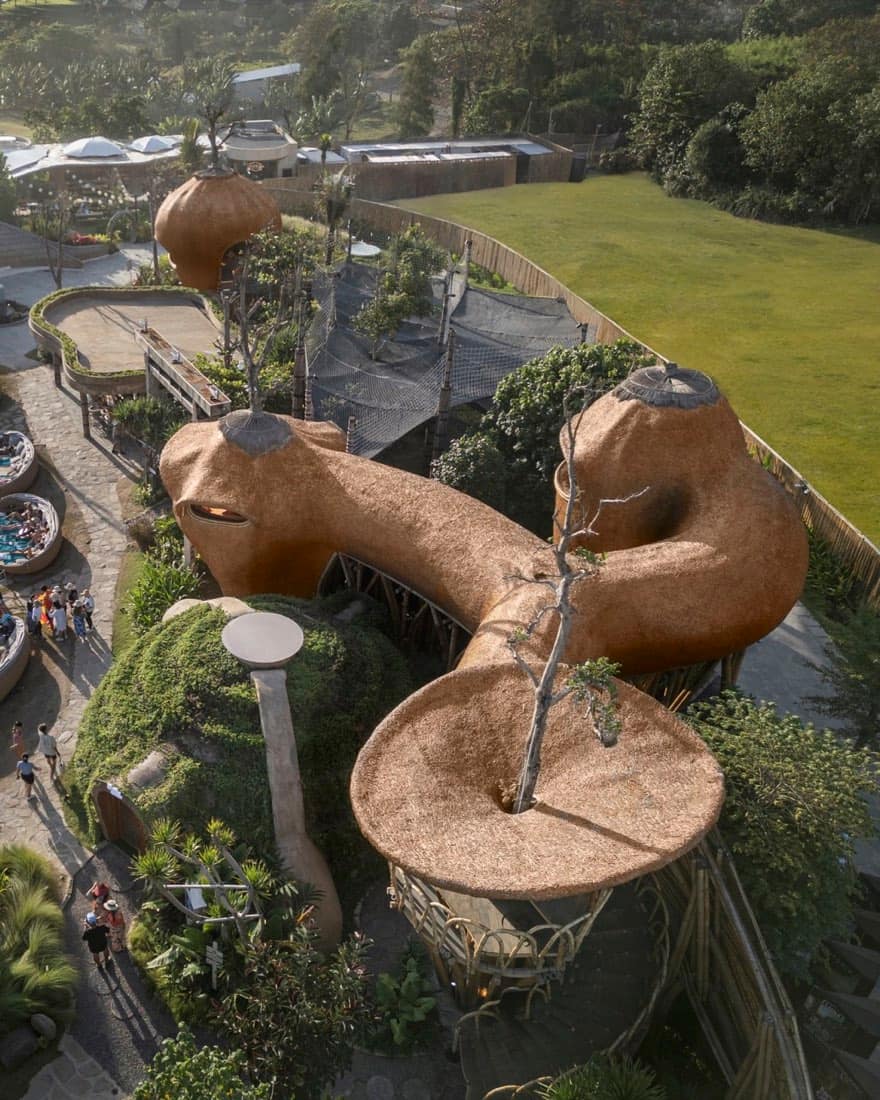 Aerial of the earthen thatched tree-pod structures and net platforms in the garden zone at Nuanu Creative City, beside Luna Beach Club