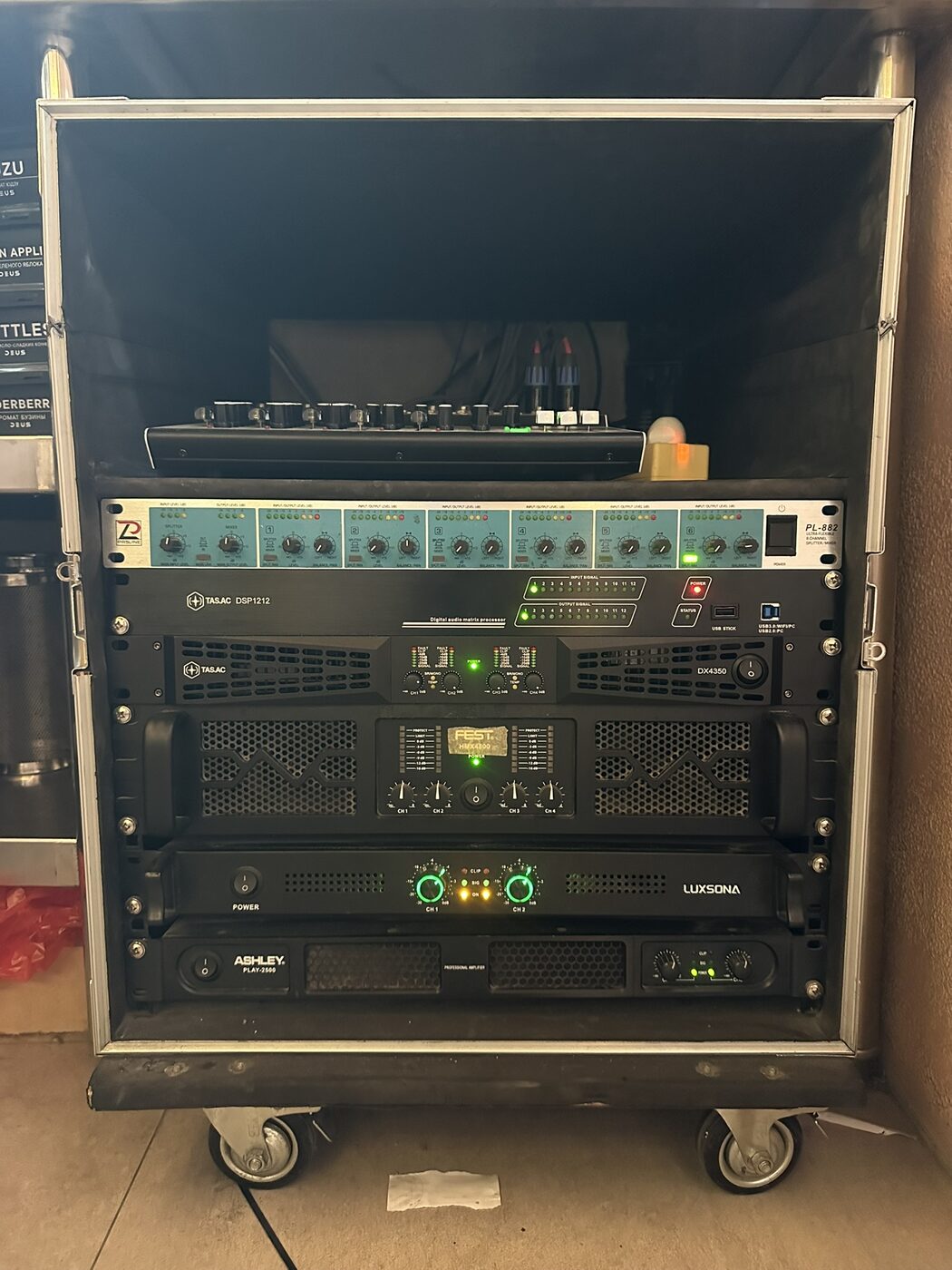 Loudspeaker system rack on casters in a SILK Restaurant back room, with a signal splitter, the TAS.AC DSP1212 digital matrix and the TAS.AC DX4350 amplifier racked together